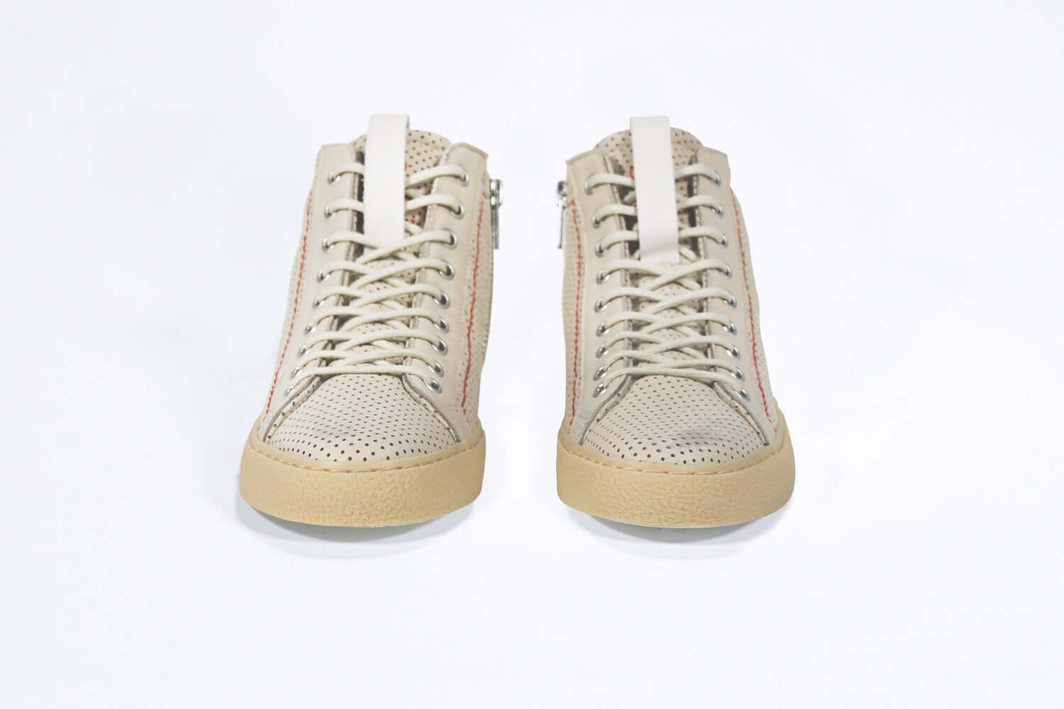 Front view of high top sneaker. Perforated milk leather sneakers with signature red stitching and pale natural rubber sole.