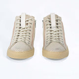 Front view of high top sneaker. Perforated milk leather sneakers with signature red stitching and pale natural rubber sole.