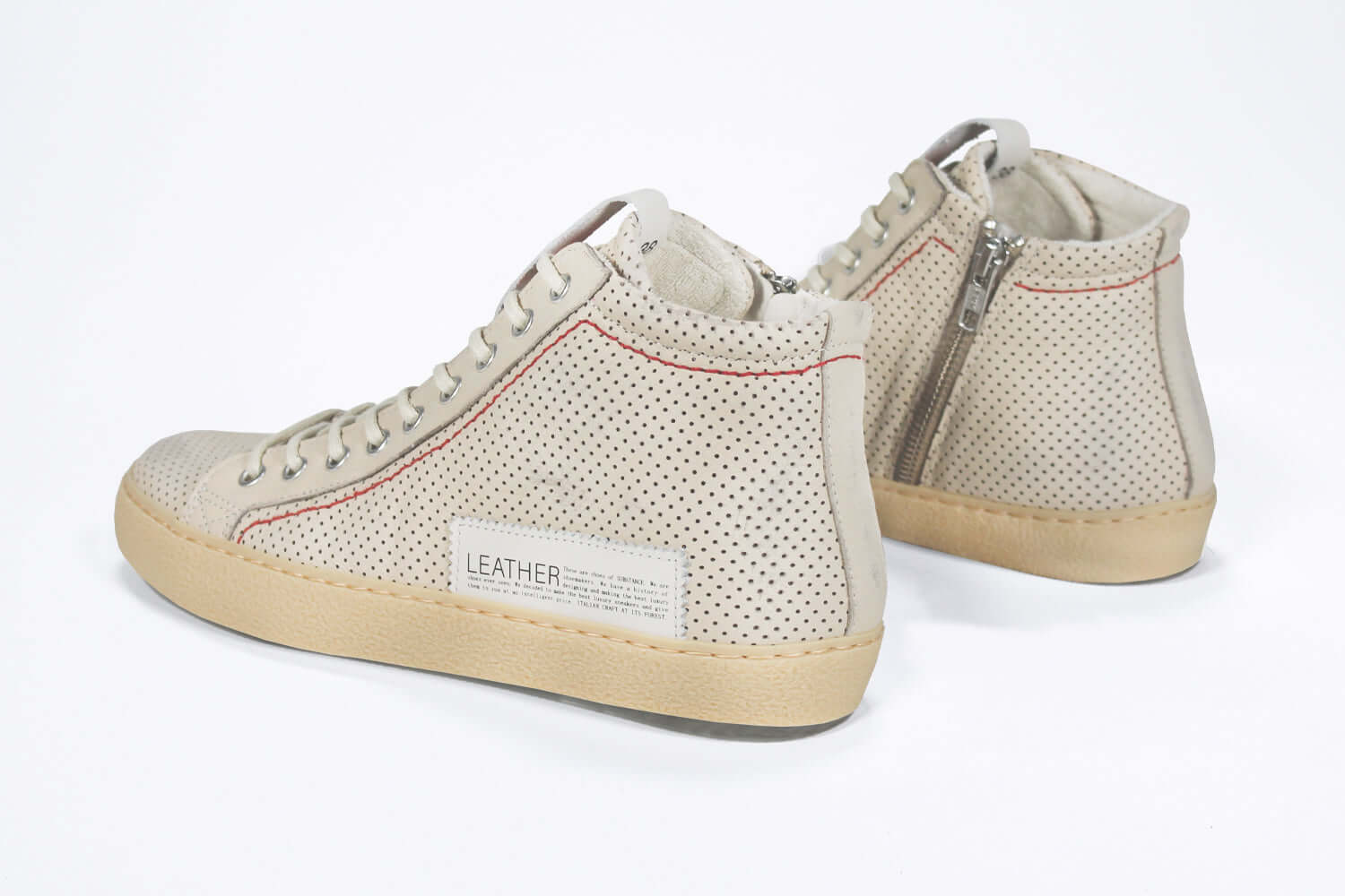 Back view of high top sneaker. Perforated milk leather sneakers with signature red stitching and pale natural rubber sole.