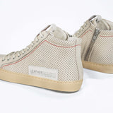 Back view of high top sneaker. Perforated milk leather sneakers with signature red stitching and pale natural rubber sole.