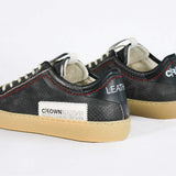 Back view of low top perforated aged black leather sneaker with red stitching detail and a pale natural rubber sole.