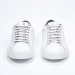 Front view of low top white sneaker with dark grey detailing and perforated crown logo on upper. Full leather upper and white rubber sole.