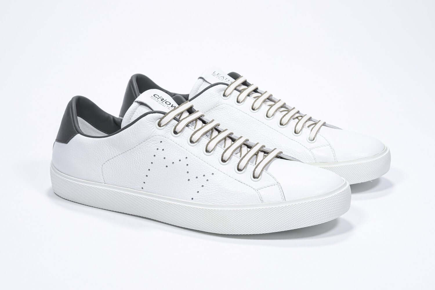 Three quarter front view of low top white sneaker with military green detailing and perforated crown logo on upper. Full leather upper and white rubber sole.