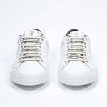 Front view of low top white sneaker with military green detailing and perforated crown logo on upper. Full leather upper and white rubber sole.