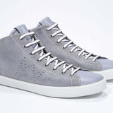 Tre quarti di un mid top grigio chiaro sneaker con tomaia in pelle scamosciata con logo a corona traforato, zip interna e suola bianca.