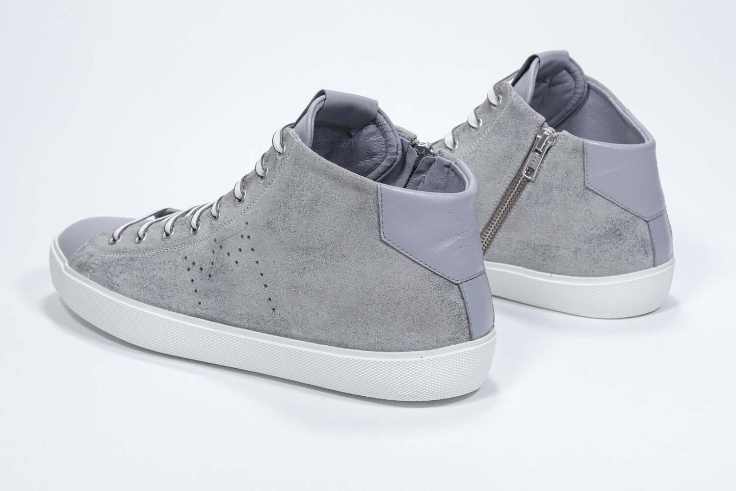Vista posteriore a tre quarti del modello mid top grigio chiaro sneaker con tomaia in pelle scamosciata con logo a corona traforato, zip interna e suola bianca.