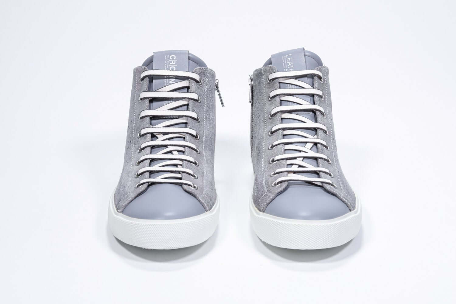 Vista frontale del mid top grigio chiaro sneaker con tomaia in pelle scamosciata con logo a corona traforato, zip interna e suola bianca.