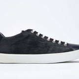 Profil latéral de la chaussure basse marine sneaker avec le logo perforé de la couronne sur l'empeigne. Tige en daim et semelle en caoutchouc blanc.