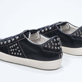 Vue de trois quarts arrière d'un modèle bas noir sneaker. Tige en cuir avec clous et semelle en caoutchouc vintage.