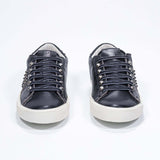 Vue de face de la chaussure noire sneaker. Tige en cuir avec clous et semelle en caoutchouc vintage.
