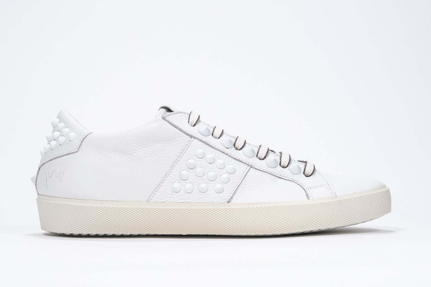 Side view of low top white sneaker. Full grain leather upper with white studs and antique white rubber sole.