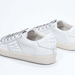 Back view of low top white sneaker. Full grain leather upper with white studs and antique white rubber sole.