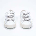 Front view of low top white sneaker. Full grain leather upper with white studs and antique white rubber sole.