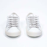 Front view of low top white sneaker. Full grain leather upper with white studs and antique white rubber sole.