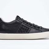 Side view of low top black sneaker. Full grain leather upper with black studs and antique white rubber sole.