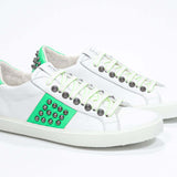 Three quarter front view of low top white and fluo green sneaker. Full grain leather upper with gun metal studs and white rubber sole.