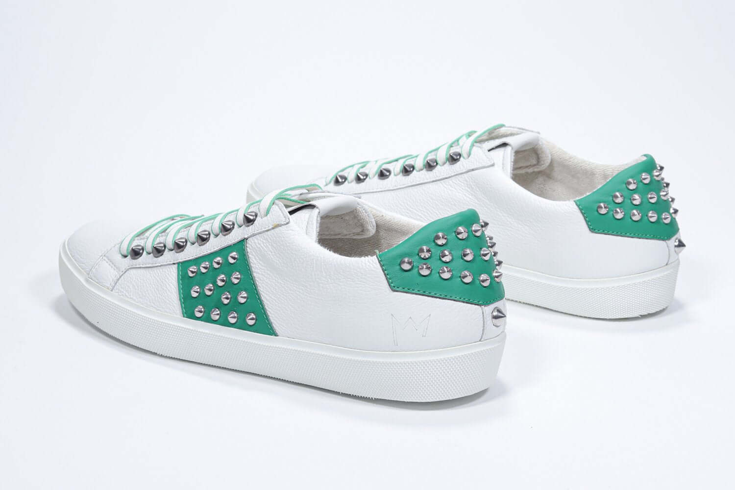Back view of low top white and green sneaker. Full grain leather upper with silver studs and white rubber sole.