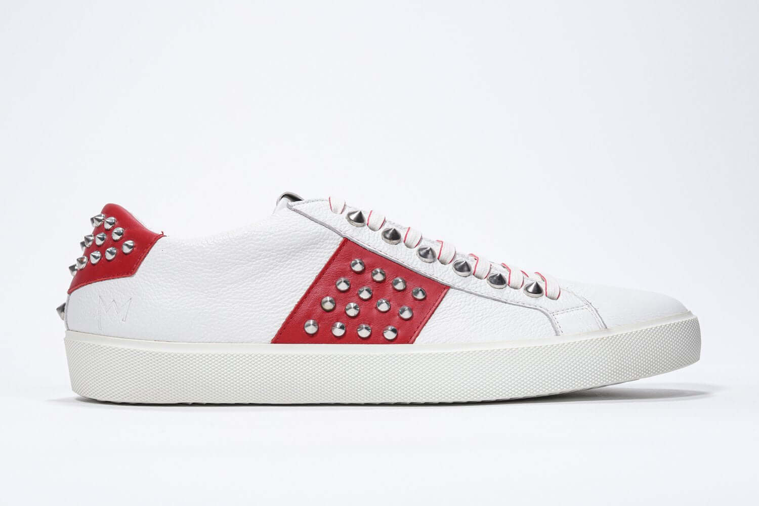 Side profile of low top white and red sneaker. Full grain leather upper with silver studs and white rubber sole.