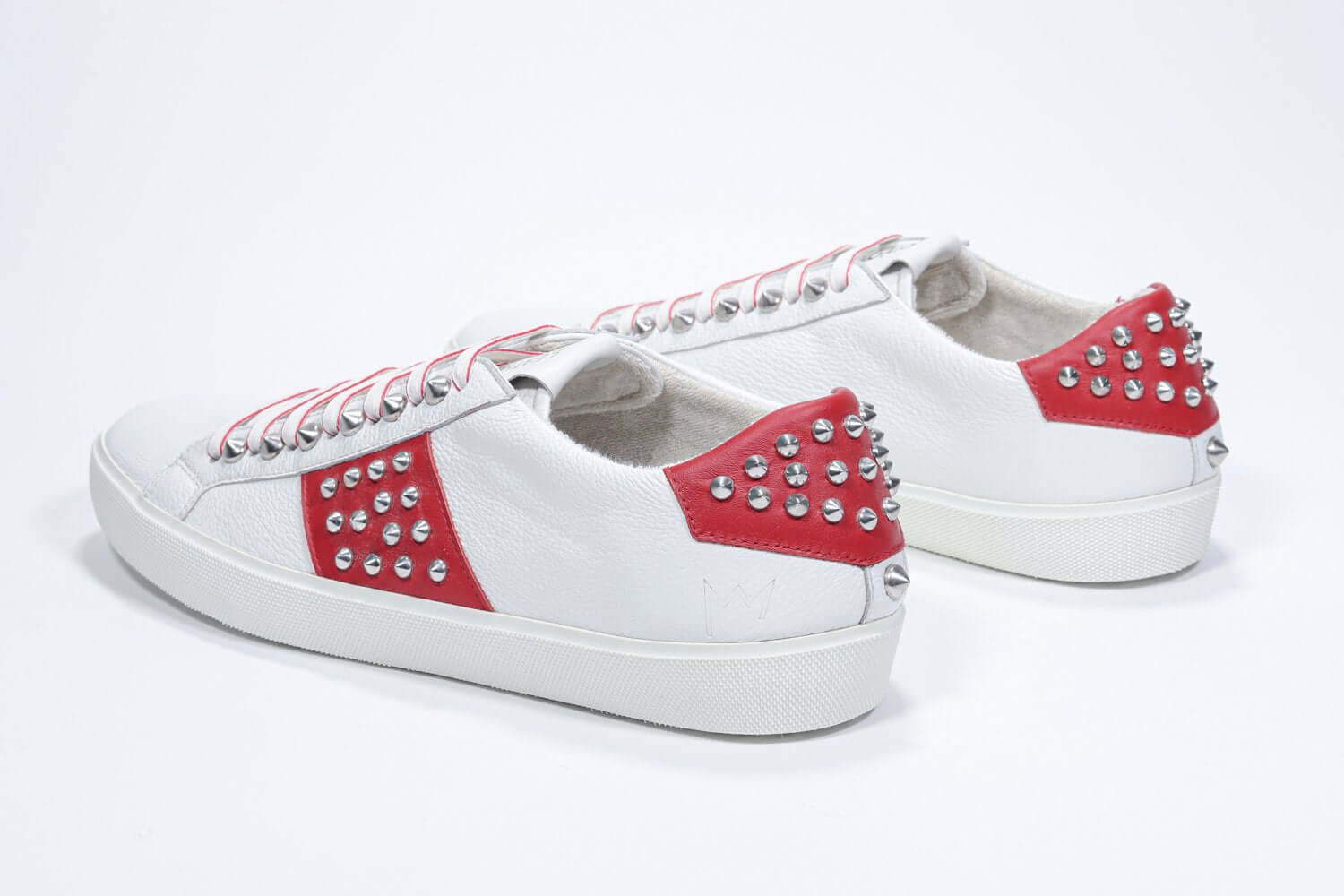 Back view of low top white and red sneaker. Full grain leather upper with silver studs and white rubber sole.