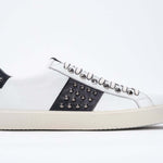 Side profile of low top white and navy sneaker. Full grain leather upper with gunmetal studs and vintage rubber sole.