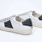 Back view of low top white and navy sneaker. Full grain leather upper with gunmetal studs and vintage rubber sole.