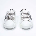Front view of low top white and navy sneaker. Full grain leather upper with gunmetal studs and vintage rubber sole.