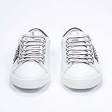 Front view of low top white and navy sneaker. Full grain leather upper with gunmetal studs and vintage rubber sole.