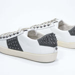 Back view of low top white and khaki sneaker. Full grain leather upper with gunmetal studs and vintage rubber sole.
