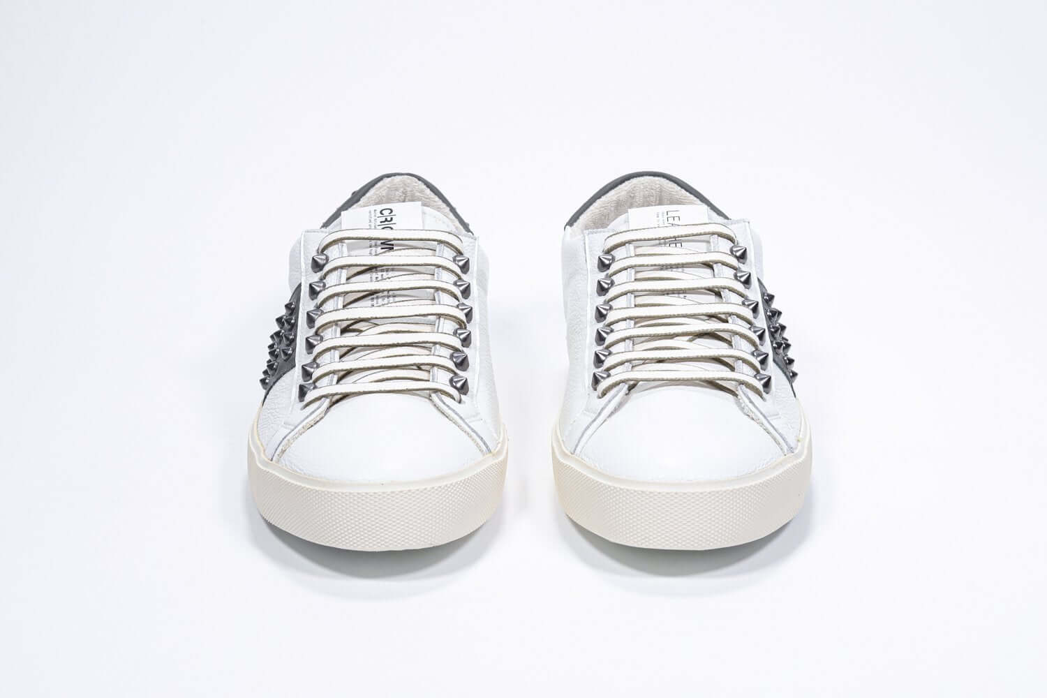 Front view of low top white and khaki sneaker. Full grain leather upper with gunmetal studs and vintage rubber sole.