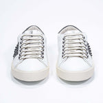 Front view of low top white and khaki sneaker. Full grain leather upper with gunmetal studs and vintage rubber sole.