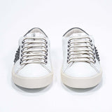 Front view of low top white and khaki sneaker. Full grain leather upper with gunmetal studs and vintage rubber sole.