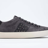 Side profile of low top grey sneaker. Suede upper with gunmetal studs and vintage rubber sole.