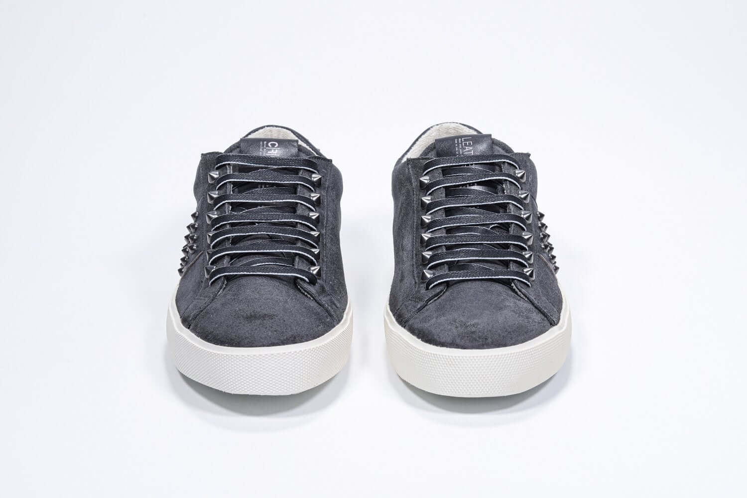 Front view of low top grey sneaker. Suede upper with gunmetal studs and vintage rubber sole.