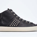 Profilo laterale di mid top nero sneaker. Tomaia in pelle con borchie, zip interna e suola in gomma vintage.