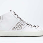 Profilo laterale di mid top bianco sneaker. Tomaia in pelle con borchie, zip interna e suola in gomma bianca.