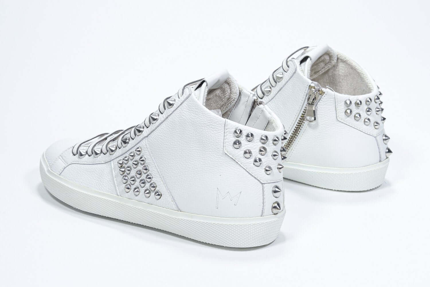 Vista posteriore di tre quarti del modello mid top bianco sneaker. Tomaia in pelle con borchie, zip interna e suola in gomma bianca.