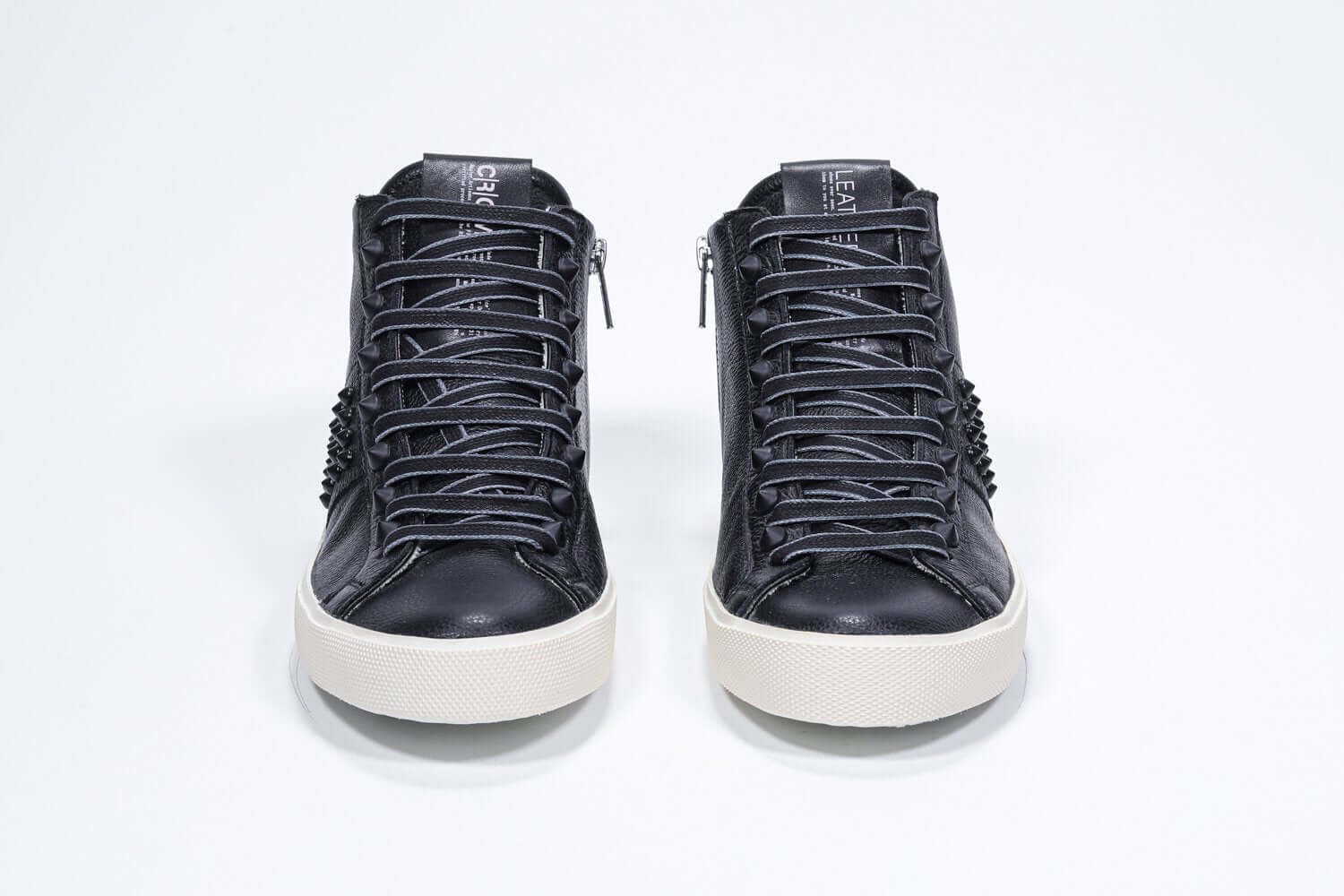 Vista frontale del mid top nero sneaker. Tomaia in pelle con borchie, zip interna e suola in gomma vintage.