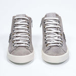 Front view of mid top beige sneaker. Full suede upper with studs, an internal zip and vintage rubber sole.