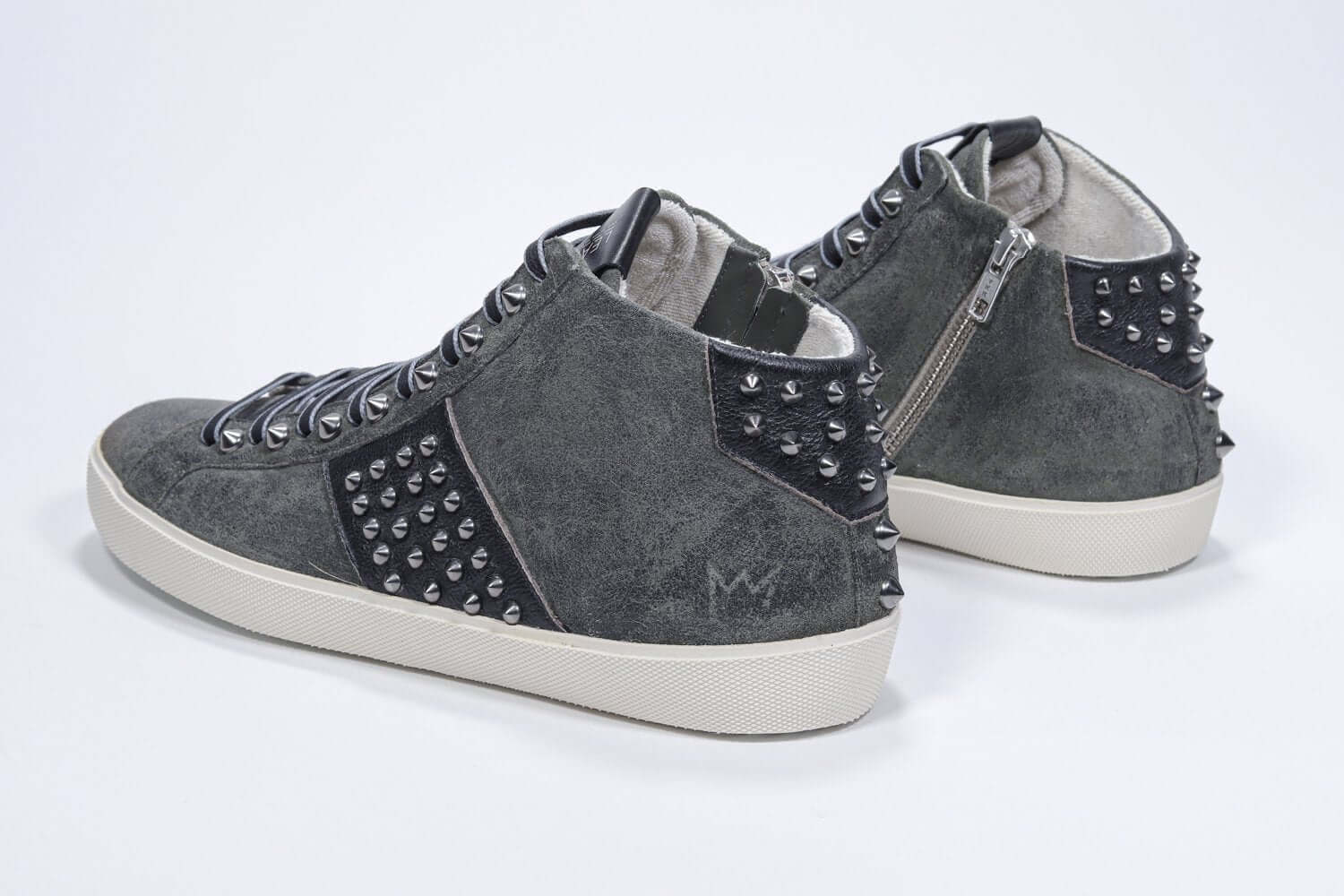 Dreiviertelansicht der Rückseite von Mid Top Military Green sneaker. Obermaterial aus Wildleder und Leder mit Nieten, einem internen Reißverschluss und einer Vintage-Gummisohle.