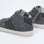 Dreiviertelansicht der Rückseite von Mid Top Military Green sneaker. Obermaterial aus Wildleder und Leder mit Nieten, einem internen Reißverschluss und einer Vintage-Gummisohle.