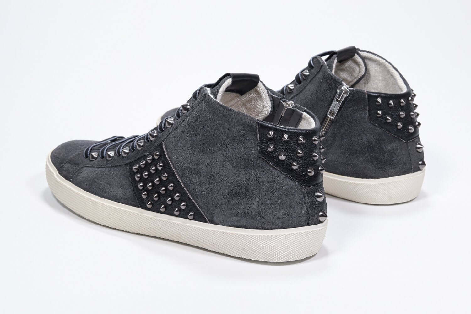 Vista posteriore di tre quarti del modello mid top grigio scuro sneaker. Tomaia in pelle e camoscio con borchie, zip interna e suola in gomma vintage.