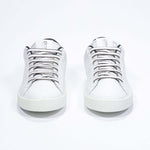 Vue de face de la chaussure blanche sneaker avec des détails noirs et le logo perforé de la couronne sur l'empeigne. Tige en cuir et semelle en caoutchouc blanc.