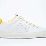 Side profile of low top white sneaker with yellow detailing and perforated crown logo on upper. Full leather upper and white rubber sole.