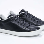 Tre quarti di BASSE  sneaker  nero con dettagli bianchi e logo della corona traforato sulla tomaia. Tomaia in pelle e suola in gomma bianca.