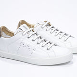 Vue de trois quarts avant de la chaussure blanche sneaker avec des détails dorés et le logo perforé de la couronne sur la tige. Tige en cuir et semelle en caoutchouc blanc.