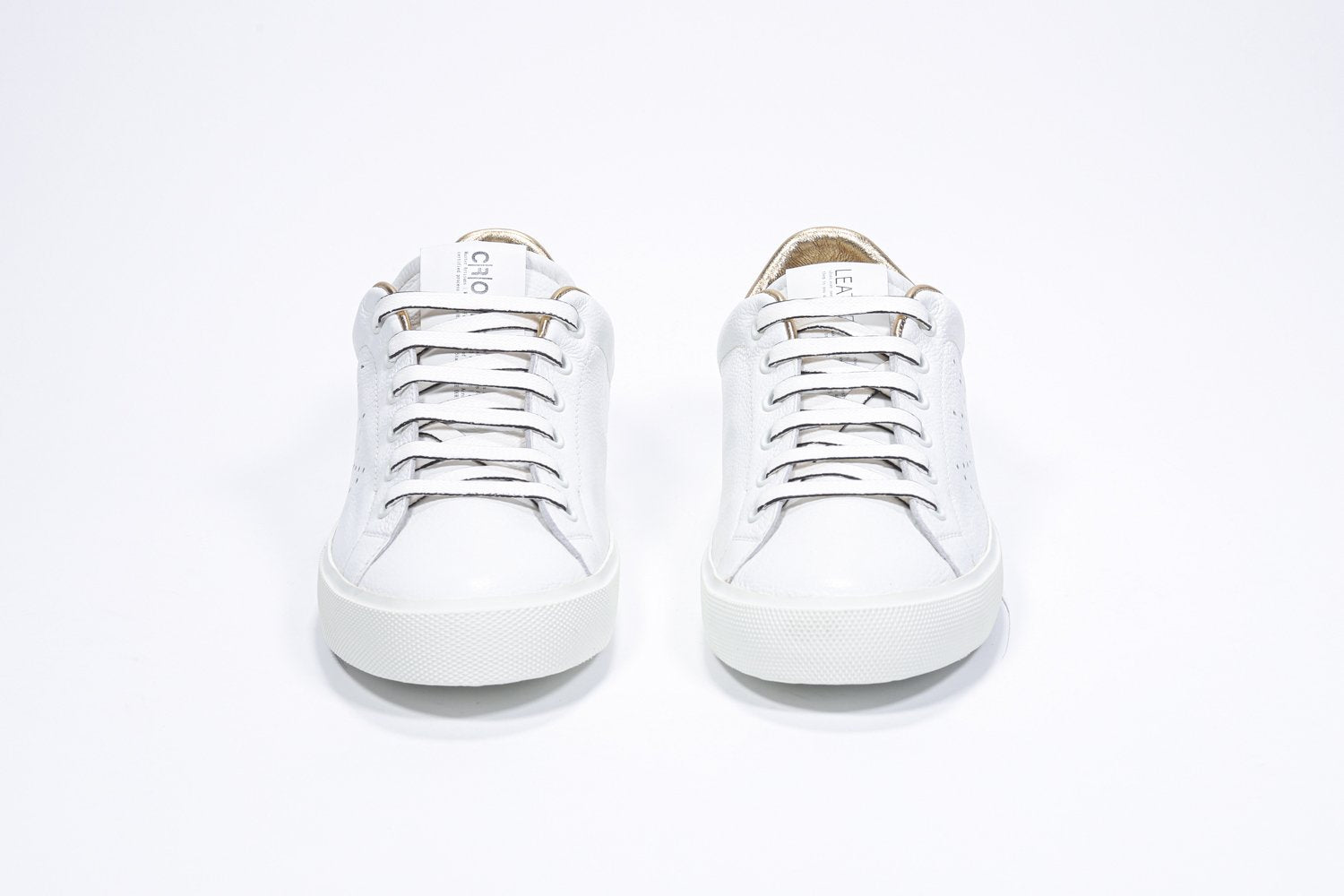 Vue de face de la chaussure blanche sneaker avec des détails dorés et le logo perforé de la couronne sur l'empeigne. Tige en cuir et semelle en caoutchouc blanc.