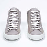 Front view of mid top beige sneaker with full suede upper with perforated crown logo, internal zip and white sole.