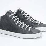 Three quarter front view of mid top military green sneaker with full suede upper with perforated crown logo, internal zip and white sole.