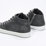 Three quarter back view of mid top military green sneaker with full suede upper with perforated crown logo, internal zip and white sole.