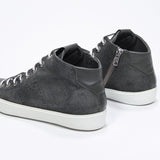 Three quarter back view of mid top military green sneaker with full suede upper with perforated crown logo, internal zip and white sole.